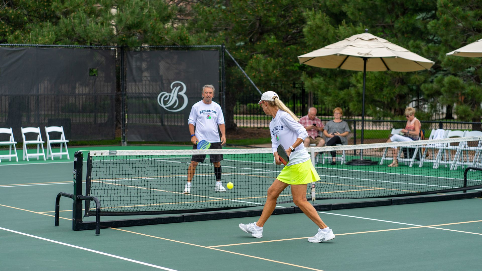 A Person Holding A Green Ball On A Court With A Racket