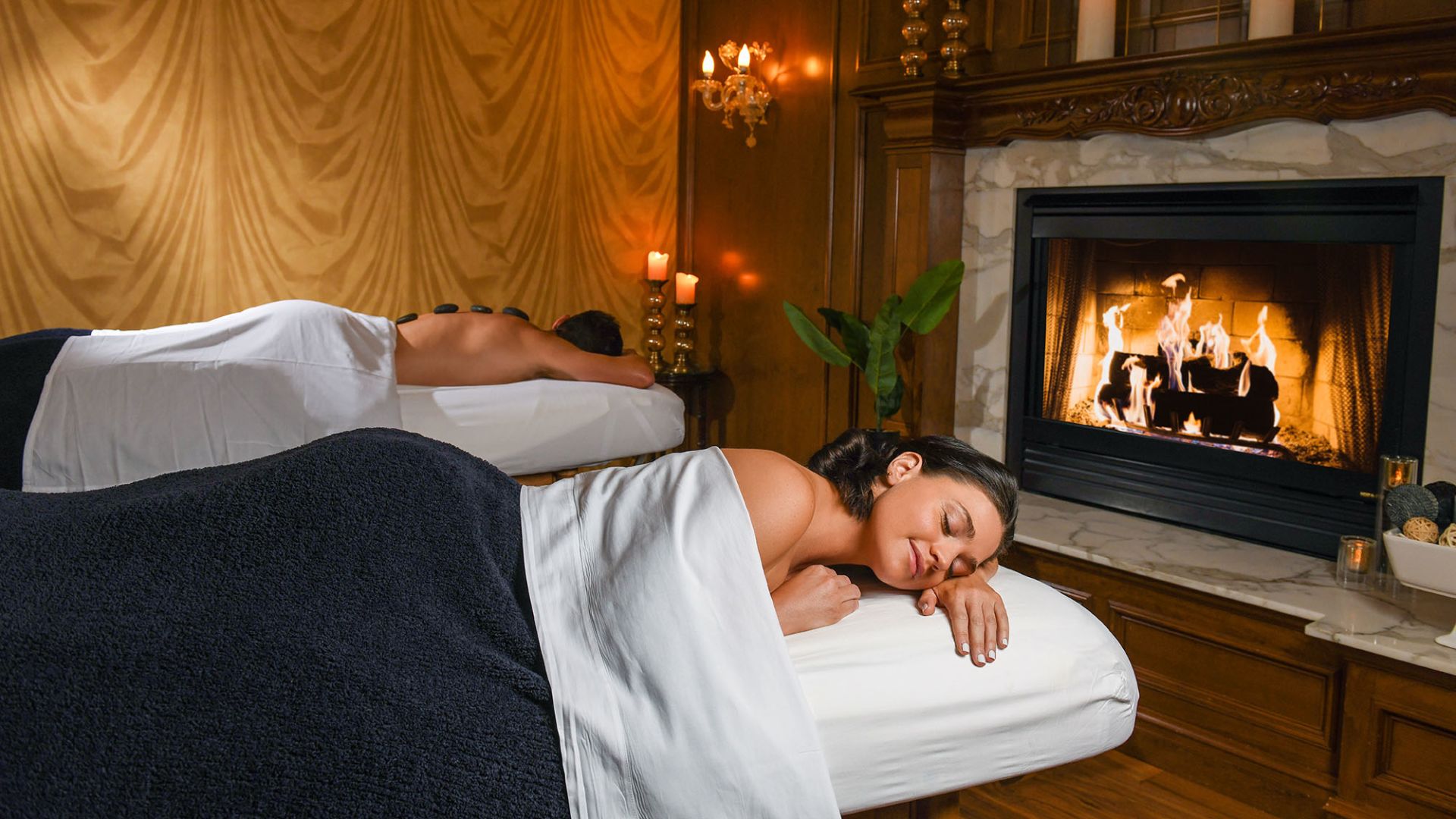 A Person Lying On A Bed In Front Of A Fireplace