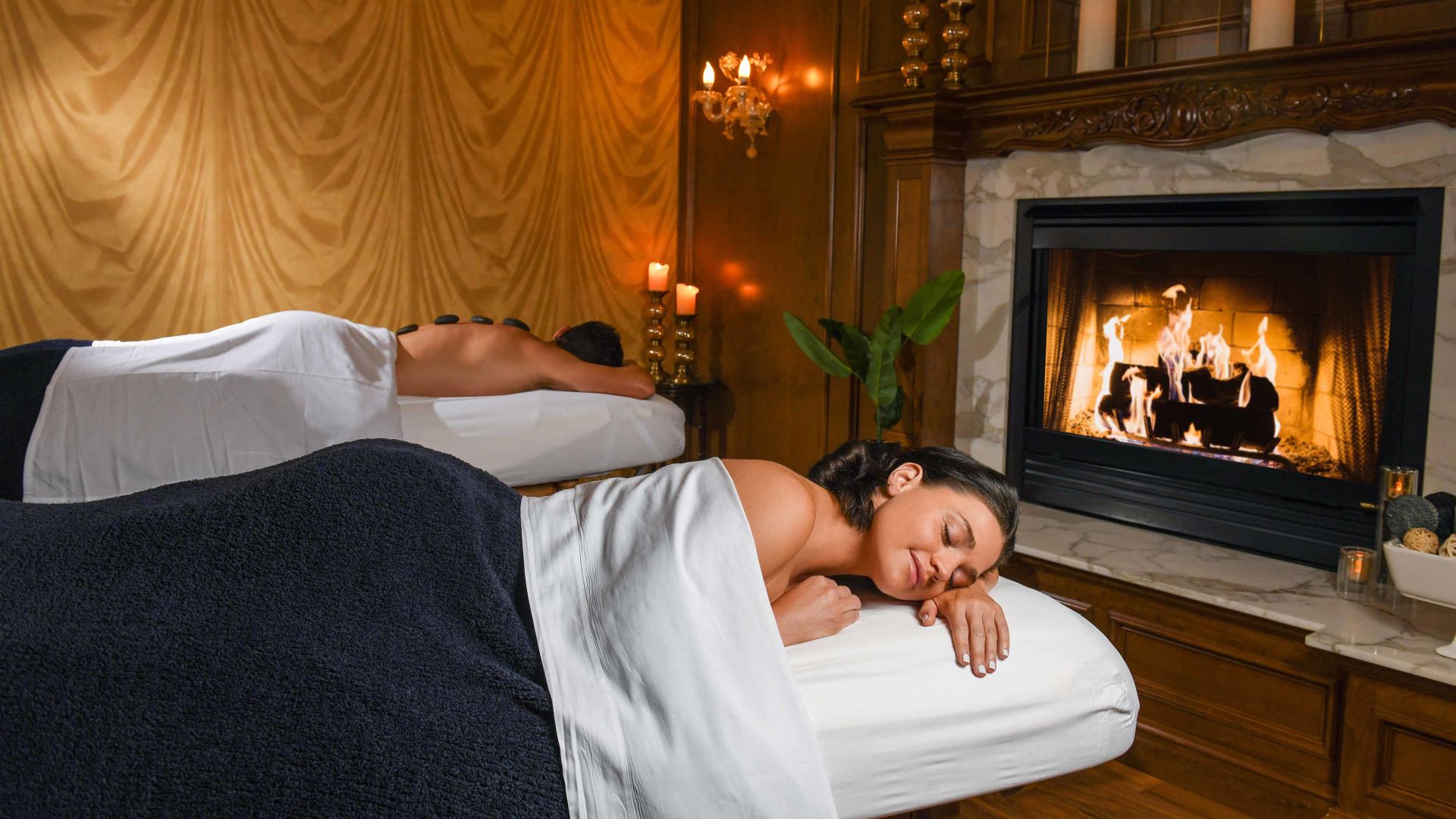 A Person Lying On A Bed In Front Of A Fireplace